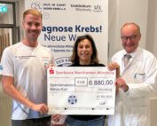 Bei der Spendenübergabe am Uniklinikum Würzburg (von links): Triathlet Niklas Karl mit Gabriele Nelkenstock und Prof. Dr. Hermann Einsele, beide von der Stiftung „Forschung hilft“. © Samantha Baumeister / UKW